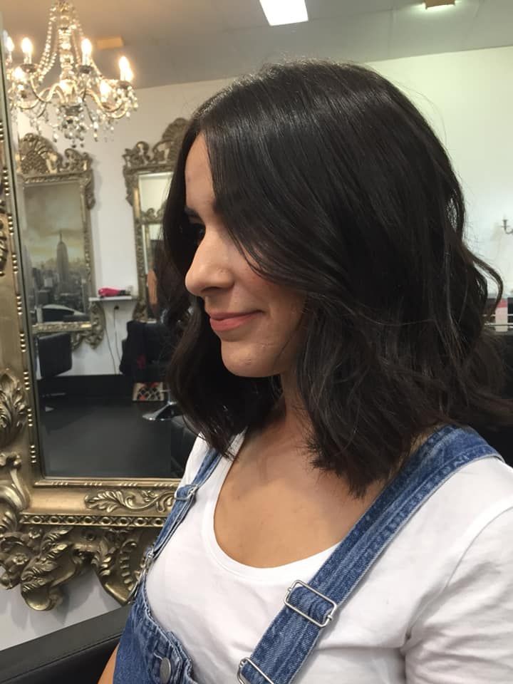 Woman With Dark Wavy Hair in a White Shirt and Denim Overalls — 5th Ave Hair Lounge in Caloundra, QLD