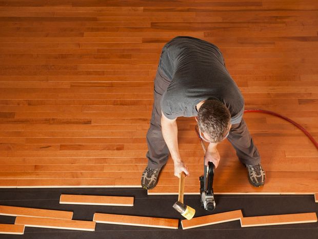 A man is hammering a nail into a wooden floor.