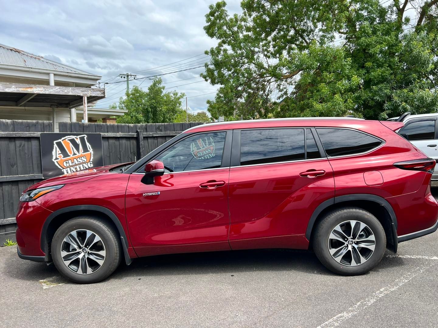 A red Toyota Highlander is parked in a parking lot next to a fence. A red Toyota Highlander is parked in a parking lot next to a fence.