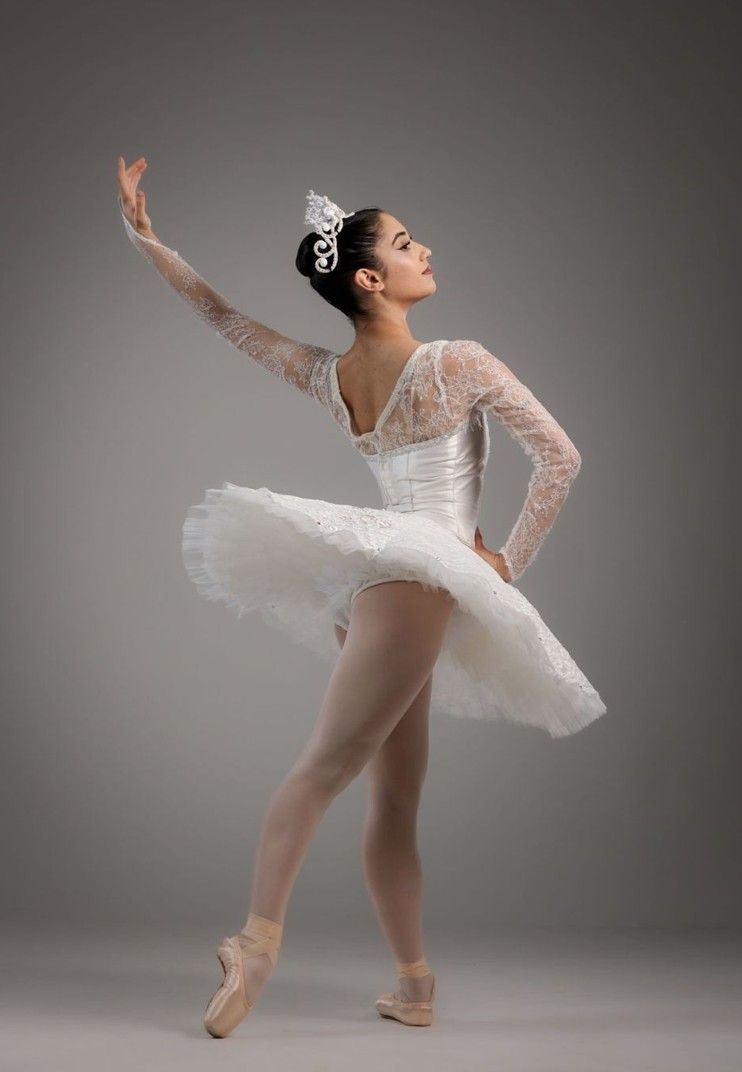 Ballerina a mezz'aria, indossa una giacca verde, una maglietta rosa e jeans. 