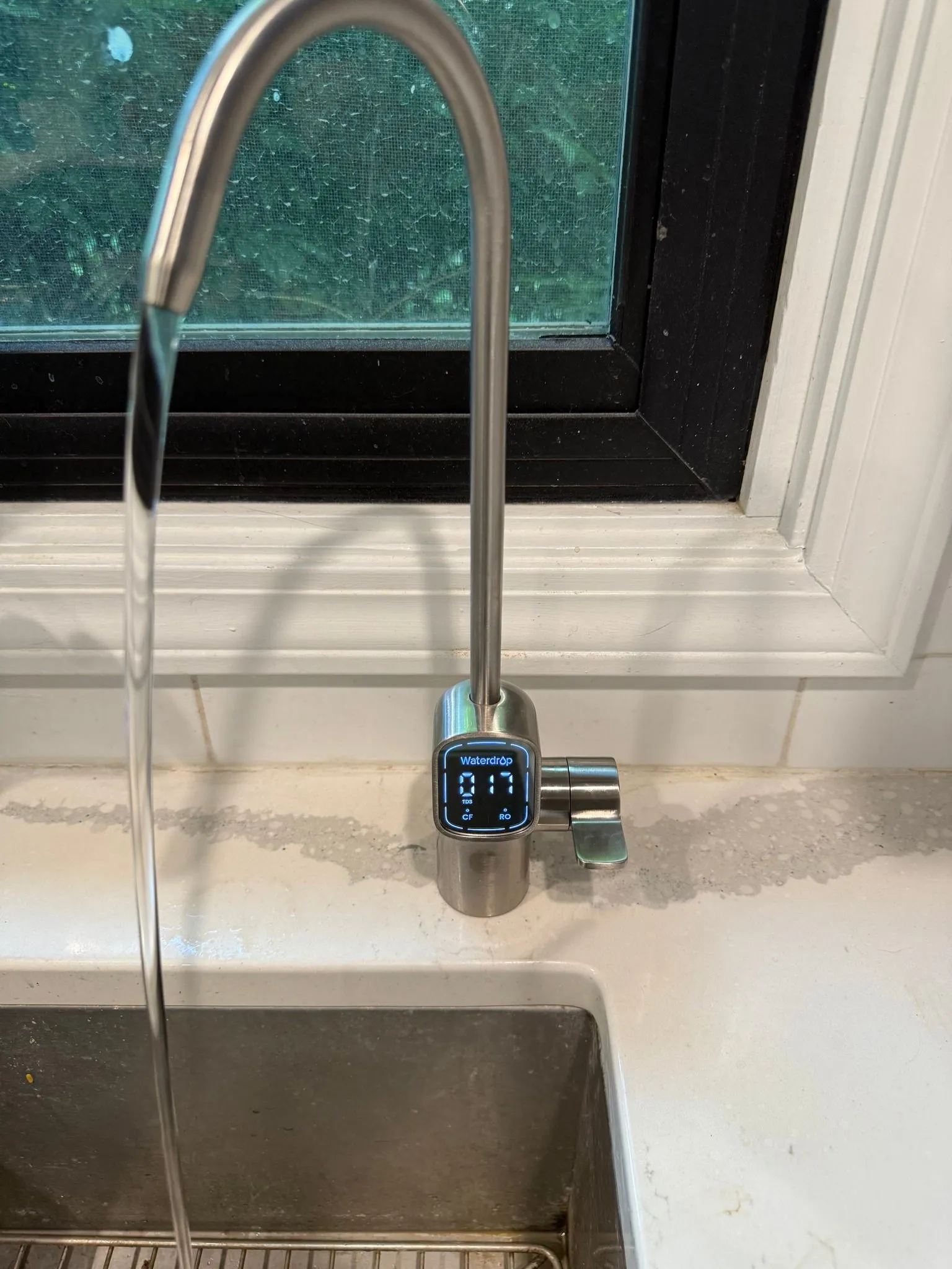 Stainless steel kitchen faucet with water flowing into a sink.