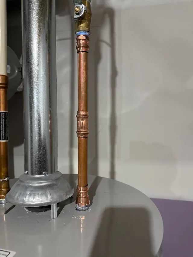 Copper plumbing pipes attached to a water heater. The pipes are vertically aligned.