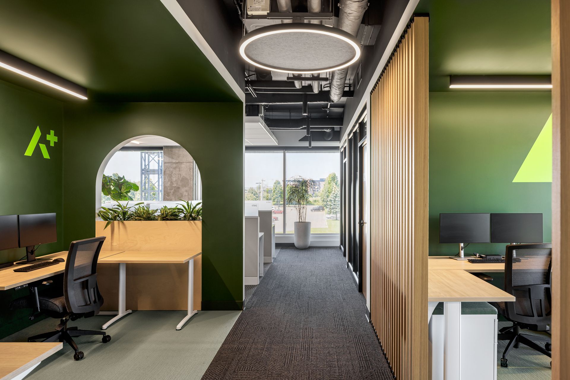 Intérieur de bureau avec murs verts, éléments en bois, bureaux et un couloir.