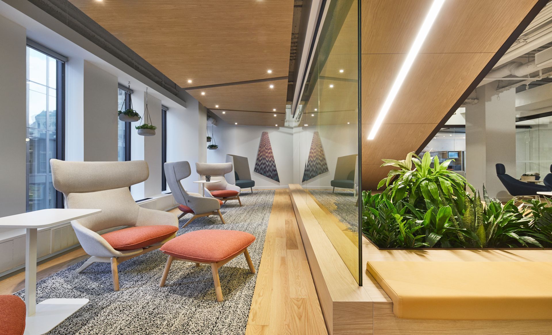 Salon de bureau moderne avec espaces de détente, plantes et éléments en bois.