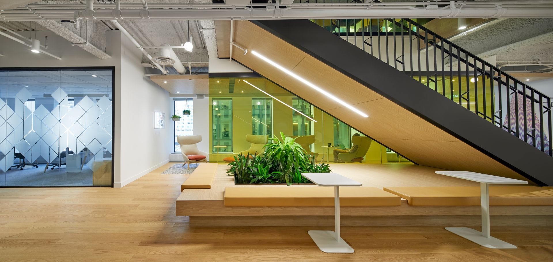 Intérieur de bureau moderne avec parquet, escalier et plantes.