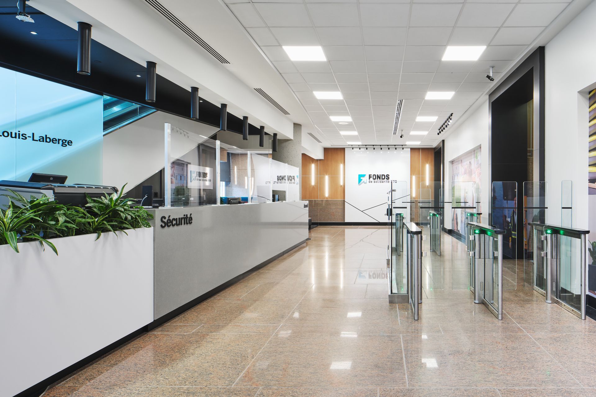 Hall d'entrée moderne avec poste de sécurité, tourniquets et sol poli.