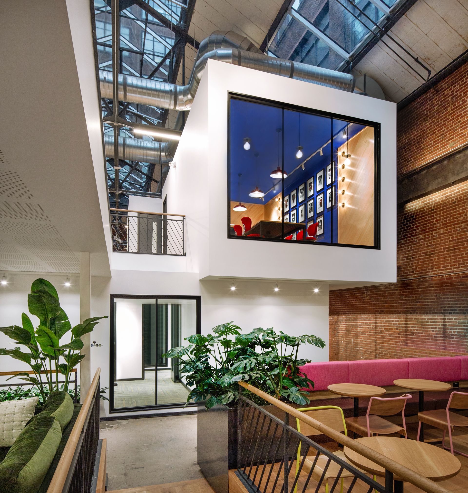 Intérieur de bureau moderne avec espace de travail surélevé, concept ouvert, mur de briques apparentes et plantes.