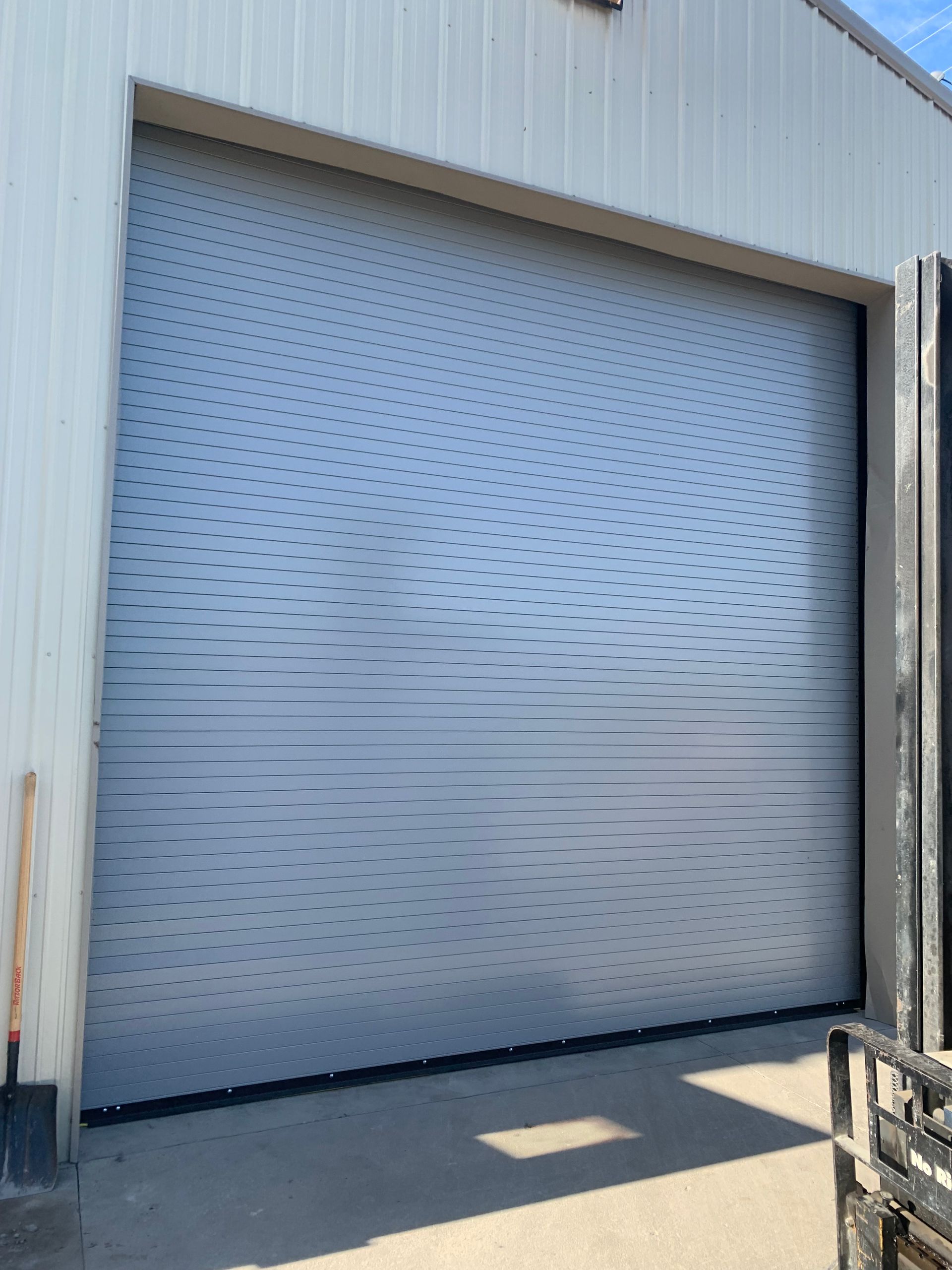 A gray garage door is closed in front of a building.