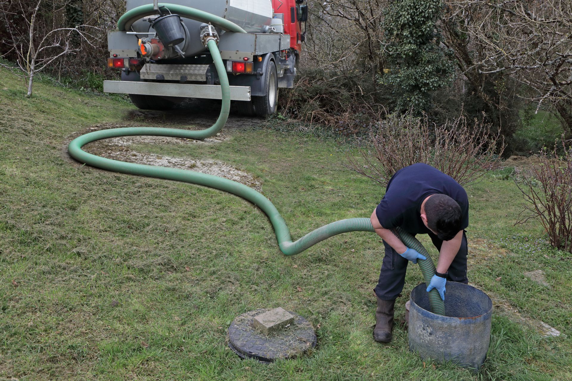 A technician pumps a septic tank, demonstrating residential septic tank pumping procedures.