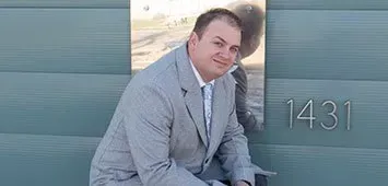 A man in a suit and tie is leaning against a wall.