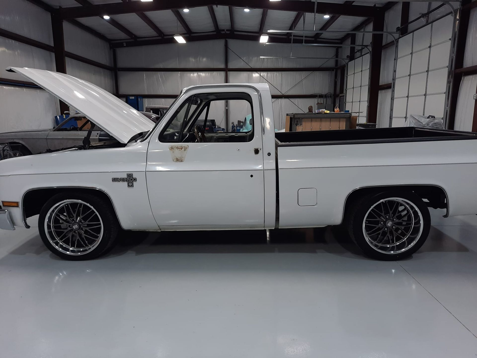 White classic pickup truck with hood open, parked in a garage or workshop.