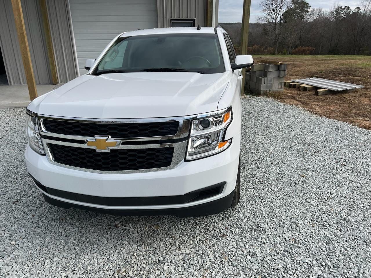 White Chevrolet SUV parked on gravel beside a building.