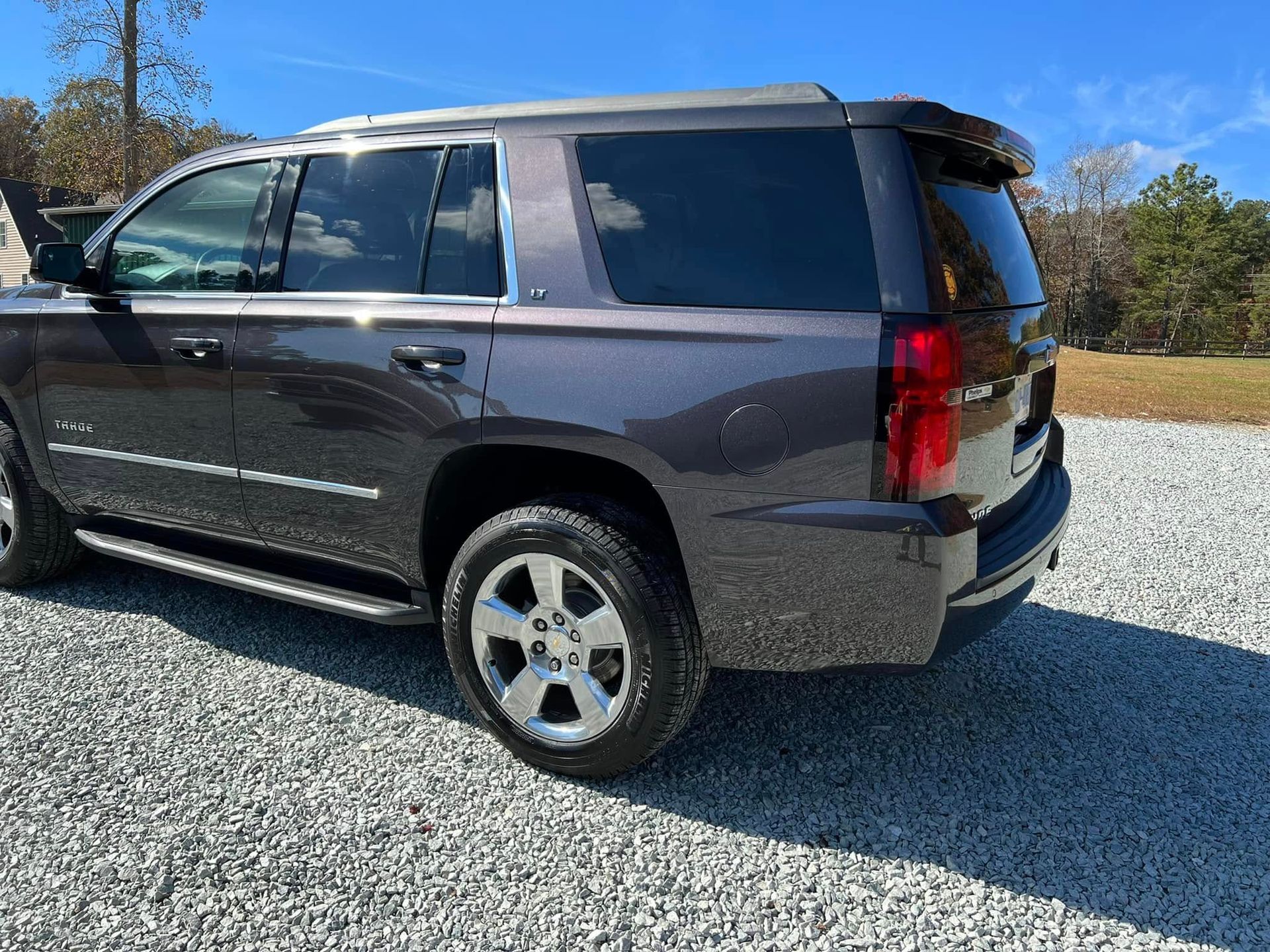 Dark gray SUV parked on gravel under a clear blue sky