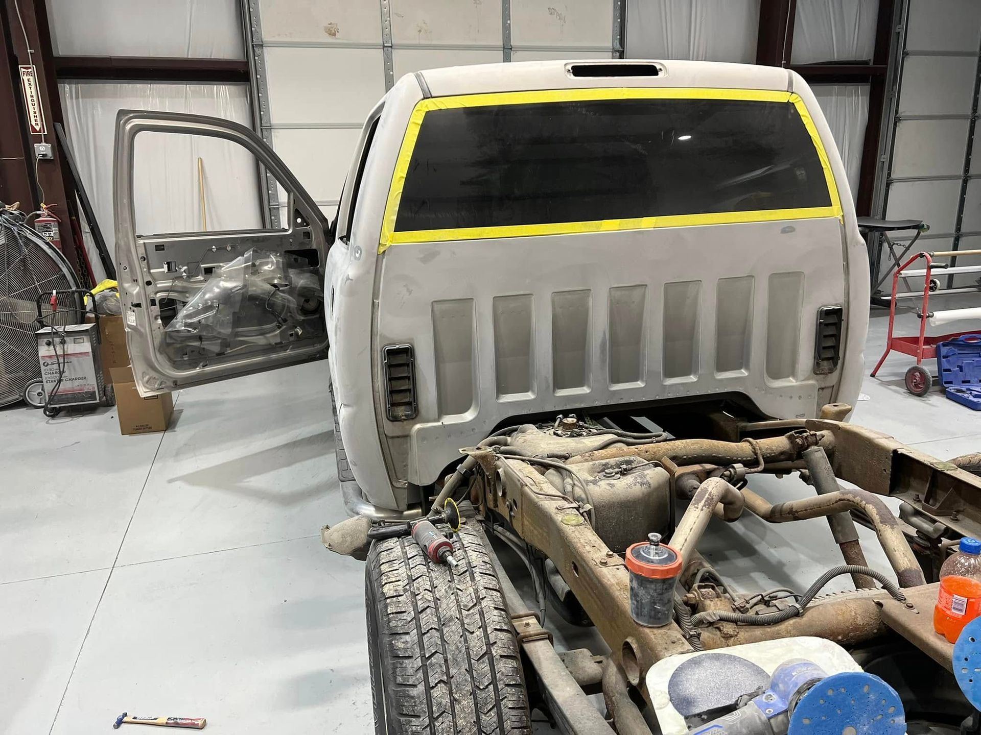 Truck cab in a repair shop with damaged front end and exposed frame components