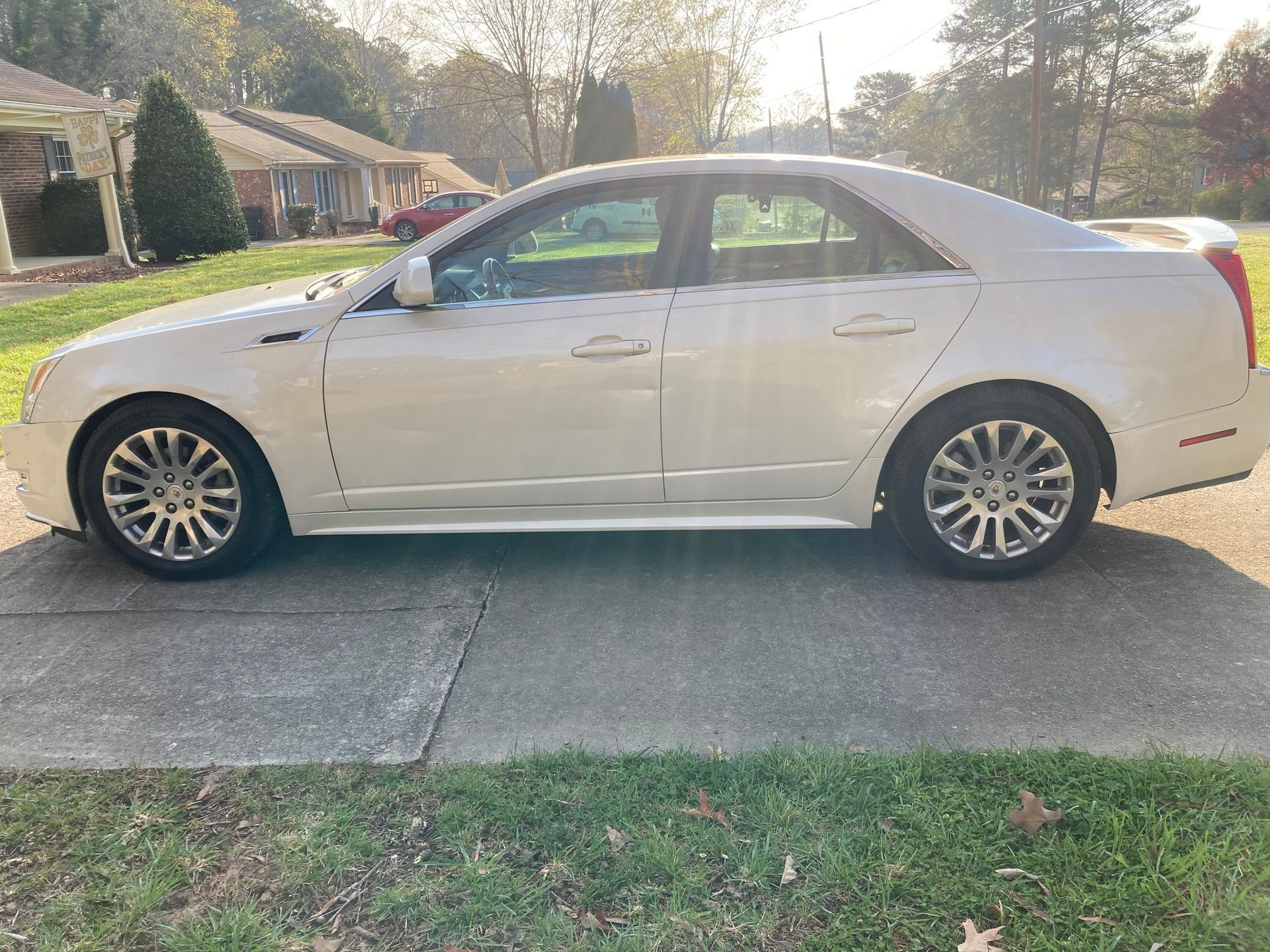 White sedan parked in a driveway on a sunny residential street