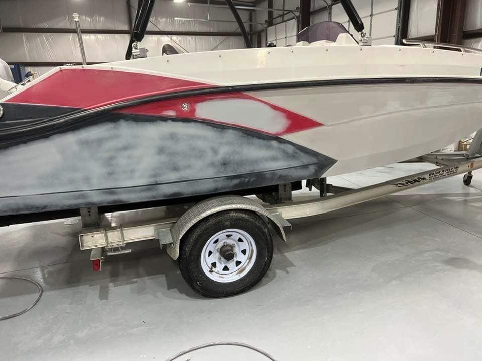Red and white speedboat on a trailer inside a garage or workshop.