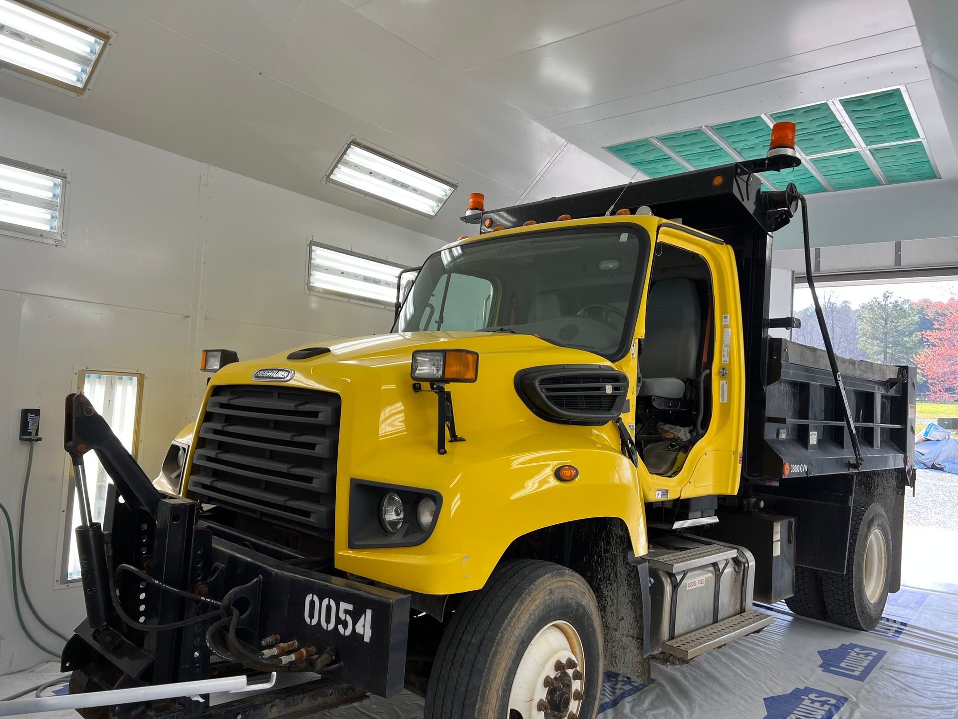 Yellow dump truck inside a garage being washed or serviced