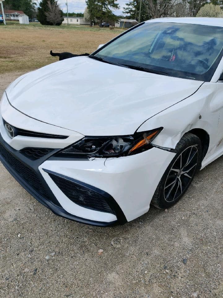 White sedan parked on gravel, front view with black grille and sporty rims