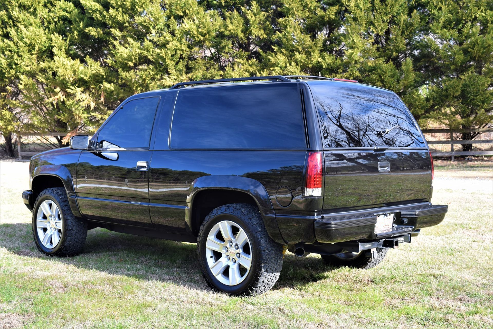 Black SUV parked on grass with trees in the background