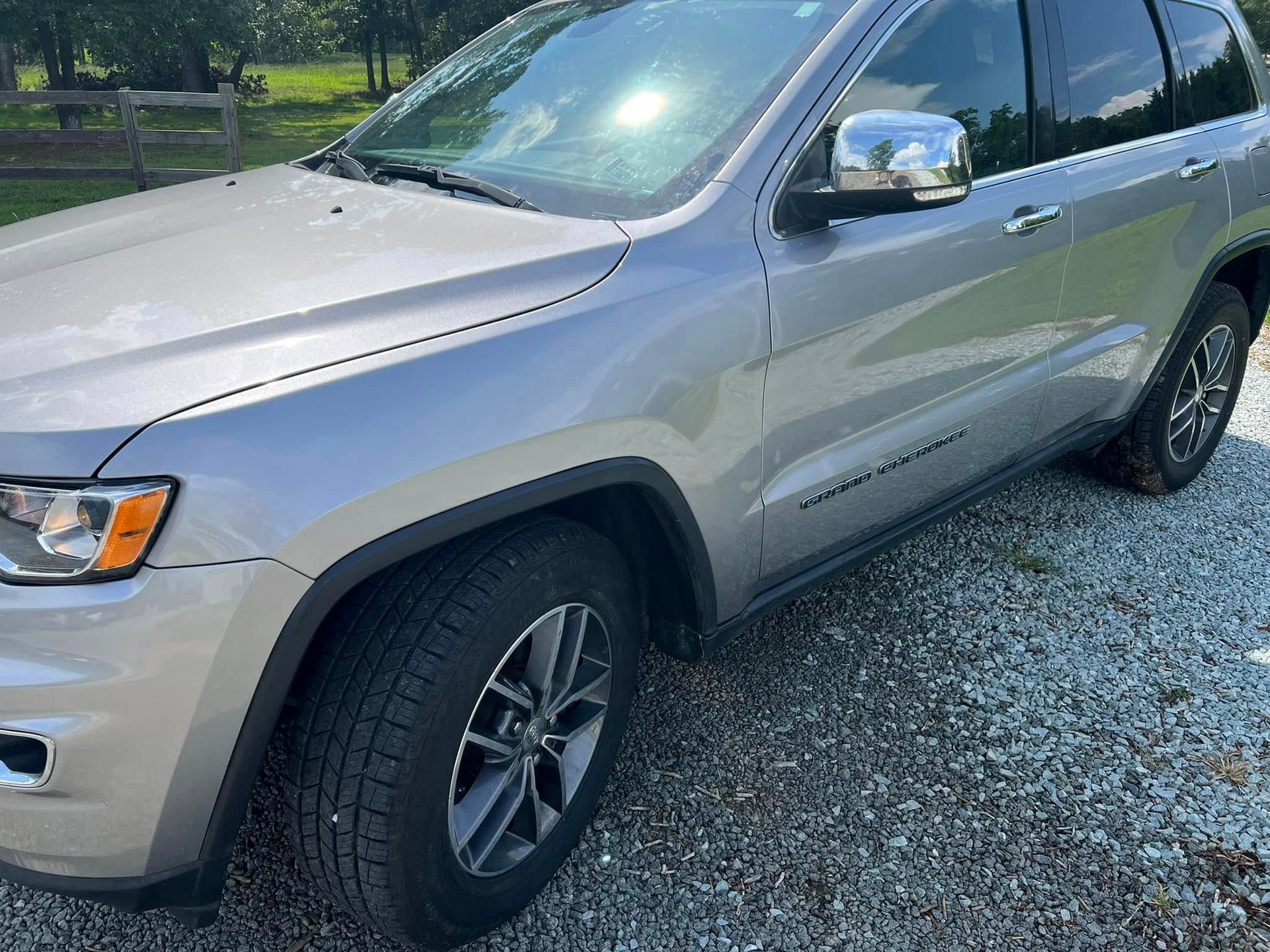 Silver SUV parked on a gravel driveway beside a road, front-left view