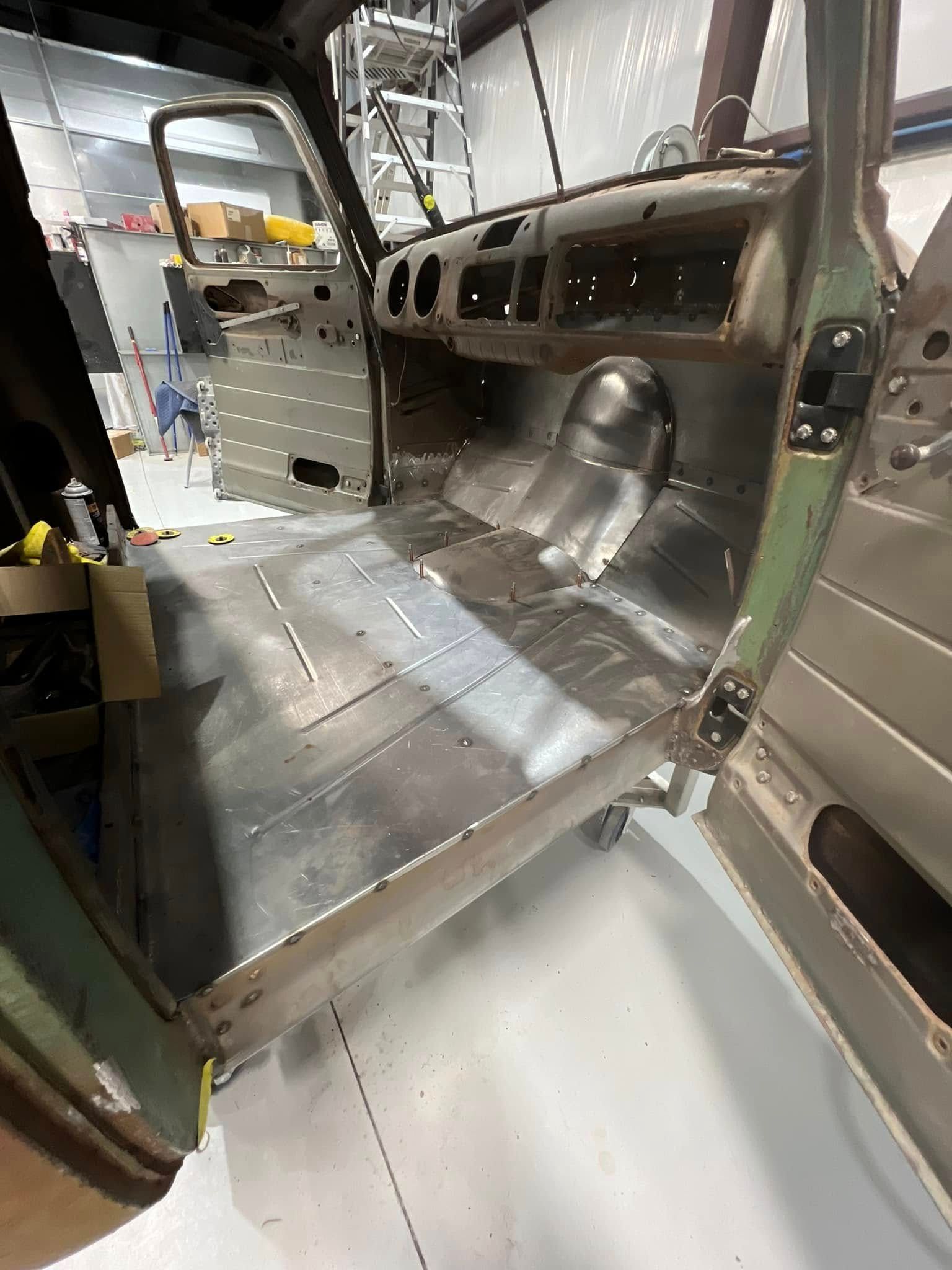 Stripped vehicle interior with bare metal floor, side panels, and exposed wiring.