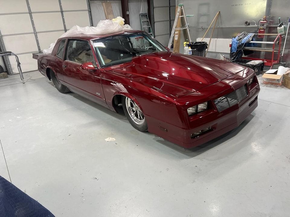 Custom maroon sports car in a workshop with foam on the roof and a glossy finish