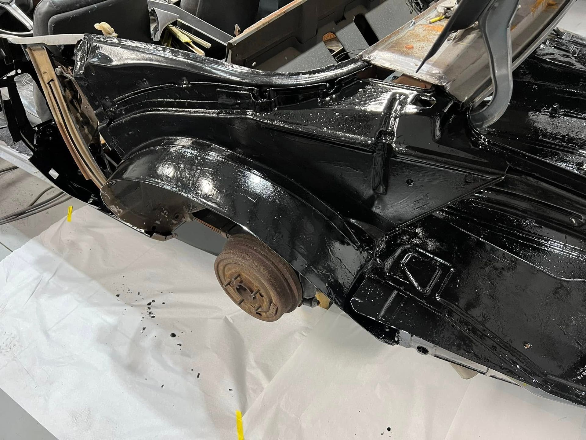 Black car fender and wheel well coated in glossy black paint during auto body repair