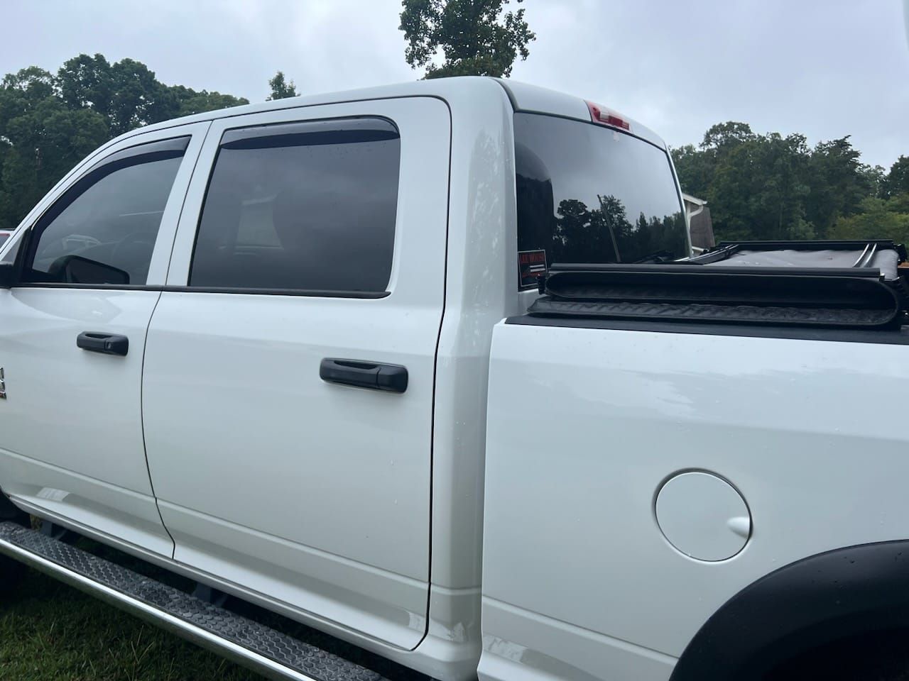 White pickup truck parked outdoors with tinted windows and a black bed cover