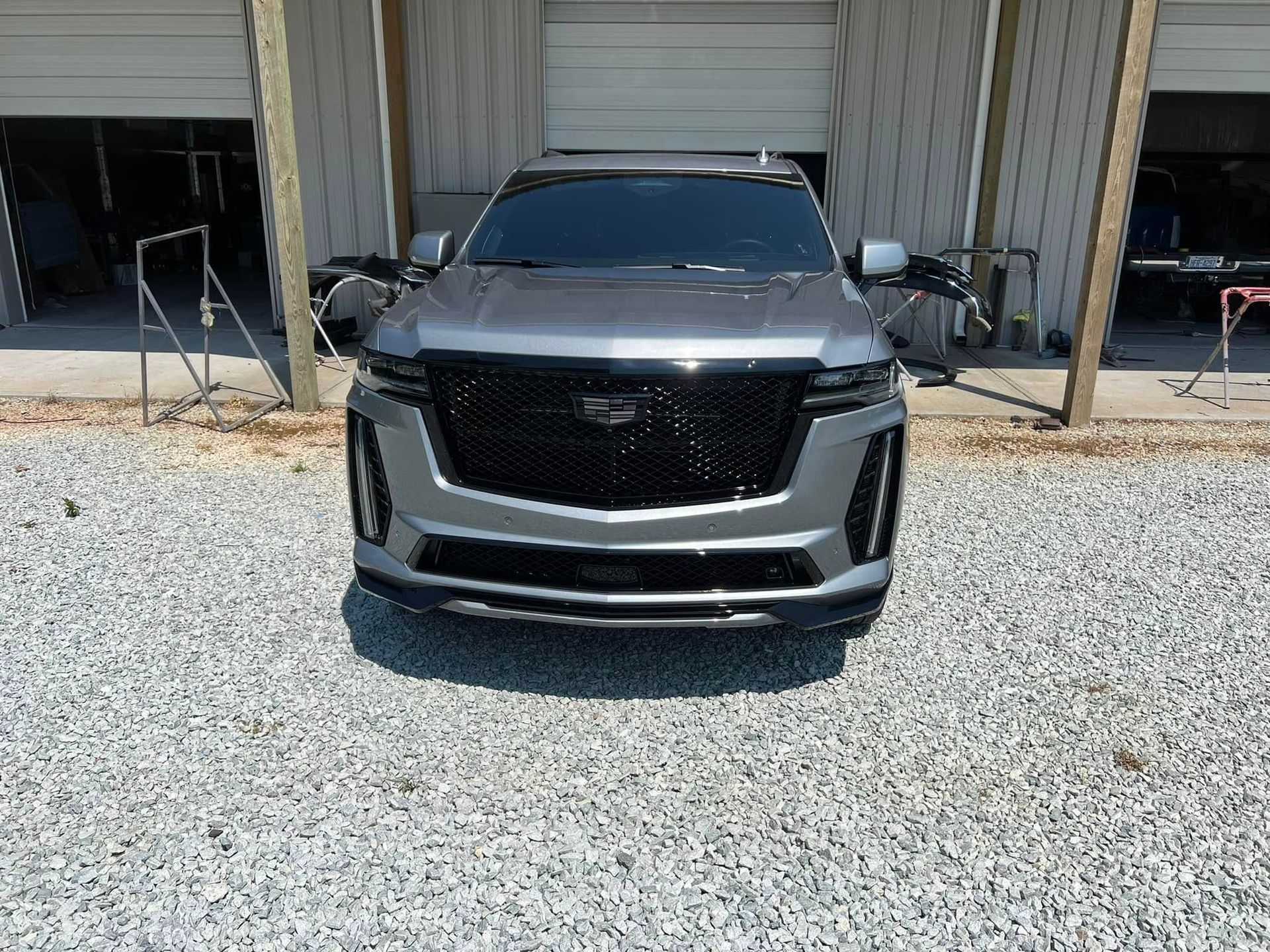 Silver SUV parked on gravel in front of an industrial garage bay