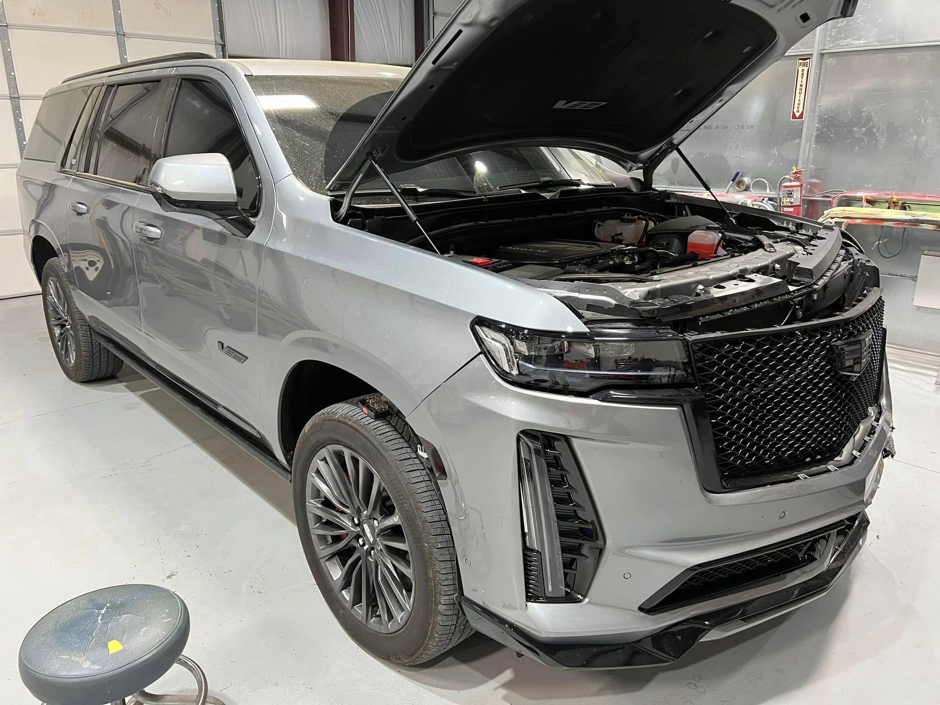 Silver SUV with hood open in a garage, showing the front and side of the vehicle