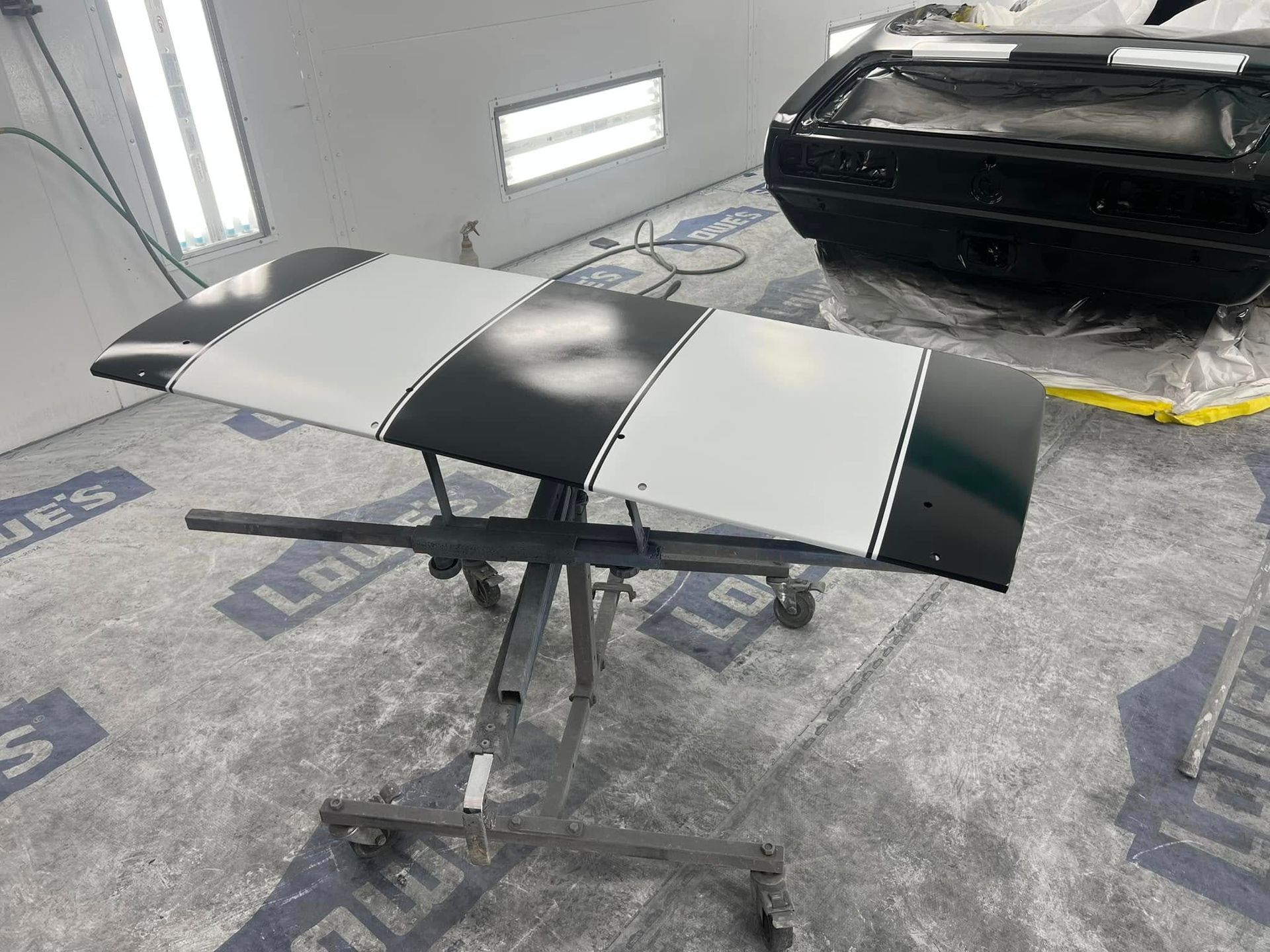 Black-and-white drone on a stand in a workshop, with a car in the background