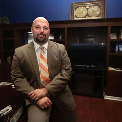 A man in a suit and tie is sitting on a desk