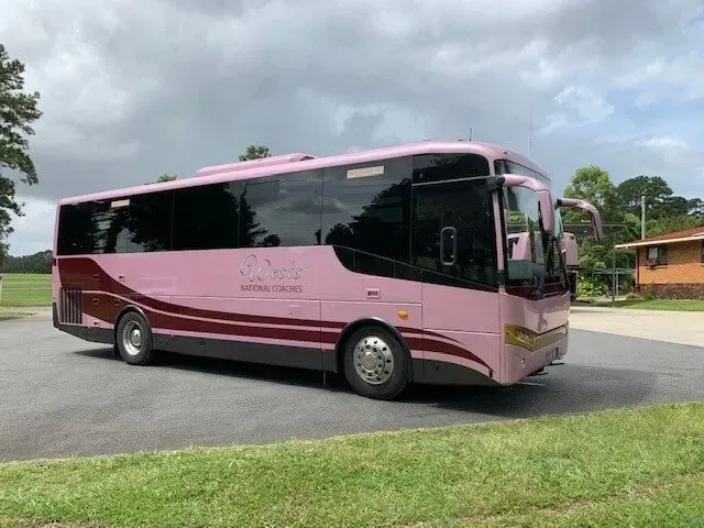 A Pink and Maroon Bus is Parked in a Parking Lot — Wests National Coaches In Chevallum, QLD