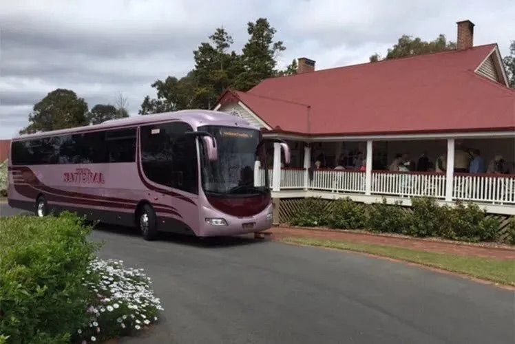 A pink bus parked outside a building with a red roof — Wests National Coaches In Chevallum, QLD