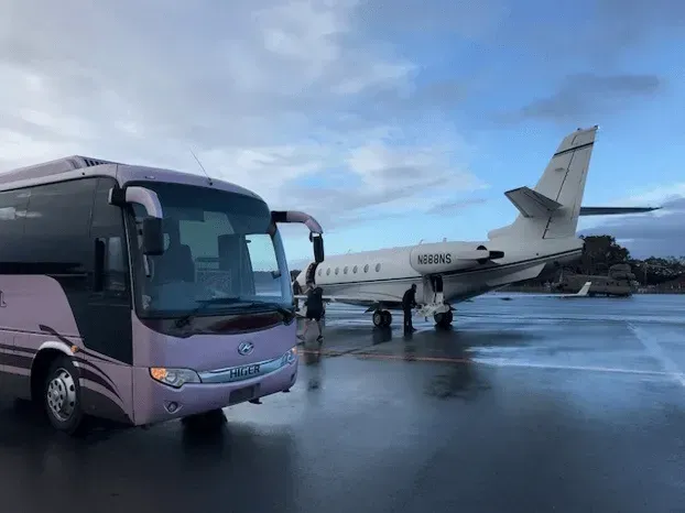A Bus is Parked Next to a Private Jet at an Airport — Wests National Coaches In Chevallum, QLD