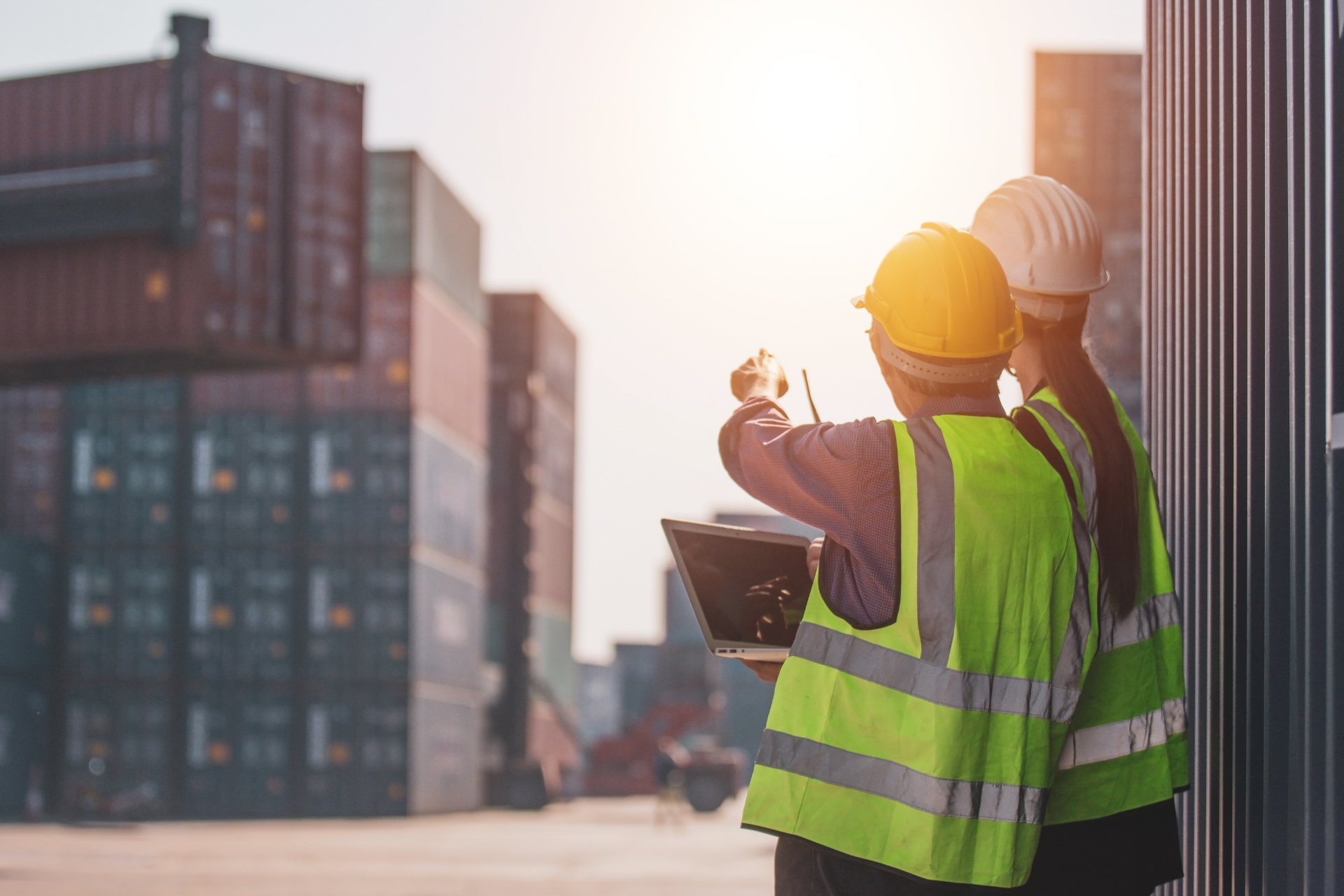 Dois trabalhadores da construção civil estão parados um ao lado do outro olhando para um tablet.