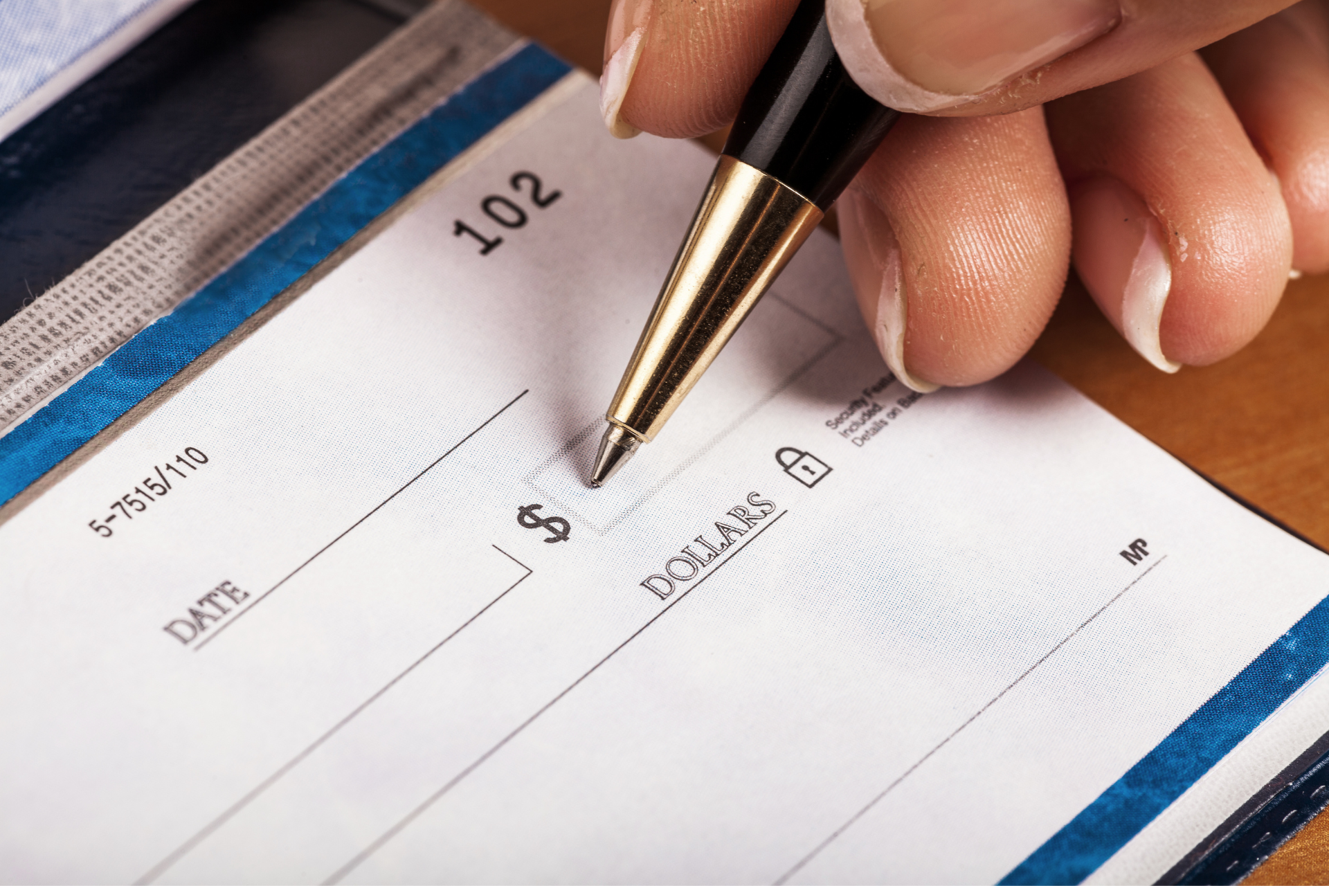 Uma pessoa está escrevendo um cheque com uma caneta.