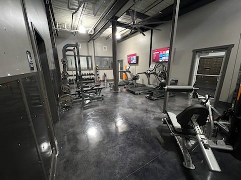 a gym filled with lots of exercise equipment and a ceiling fan .