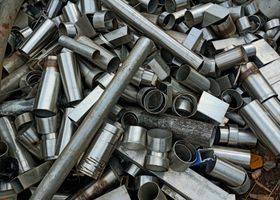 Montón de accesorios y restos de tuberías metálicas variadas, en su mayoría plateadas y grises.