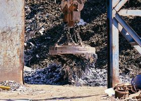 La pala de una excavadora levanta una losa de hormigón entre los escombros de una obra de demolición.