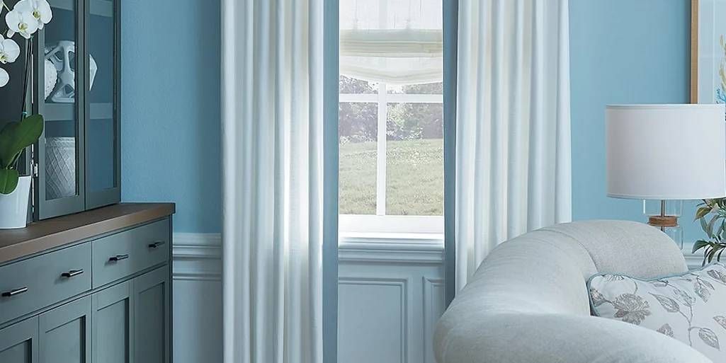 Living room window covered with a window shade and custom drapery.