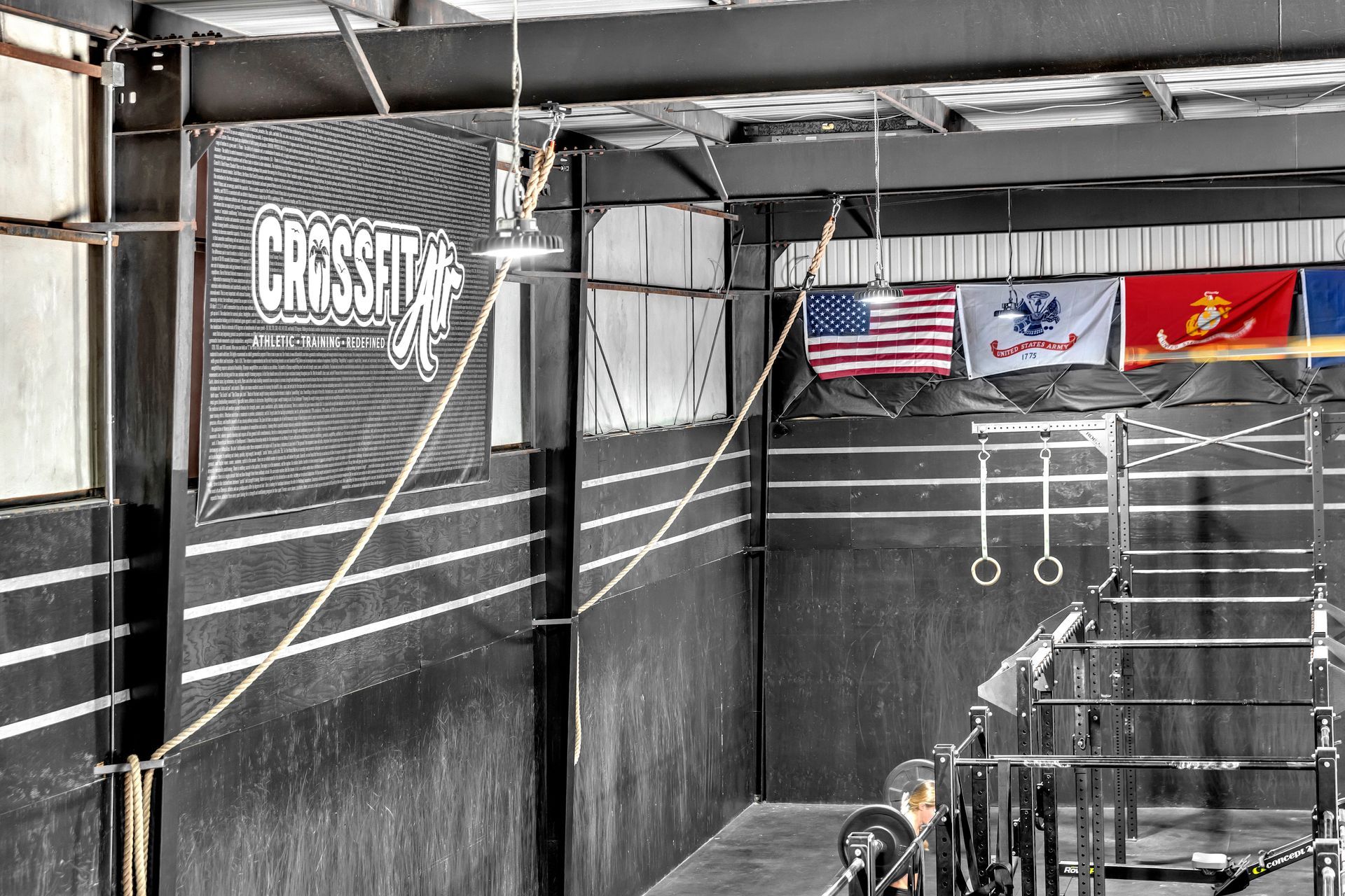 CrossFit ATR gym interior with hanging ropes, rings, flags, and black workout rigs