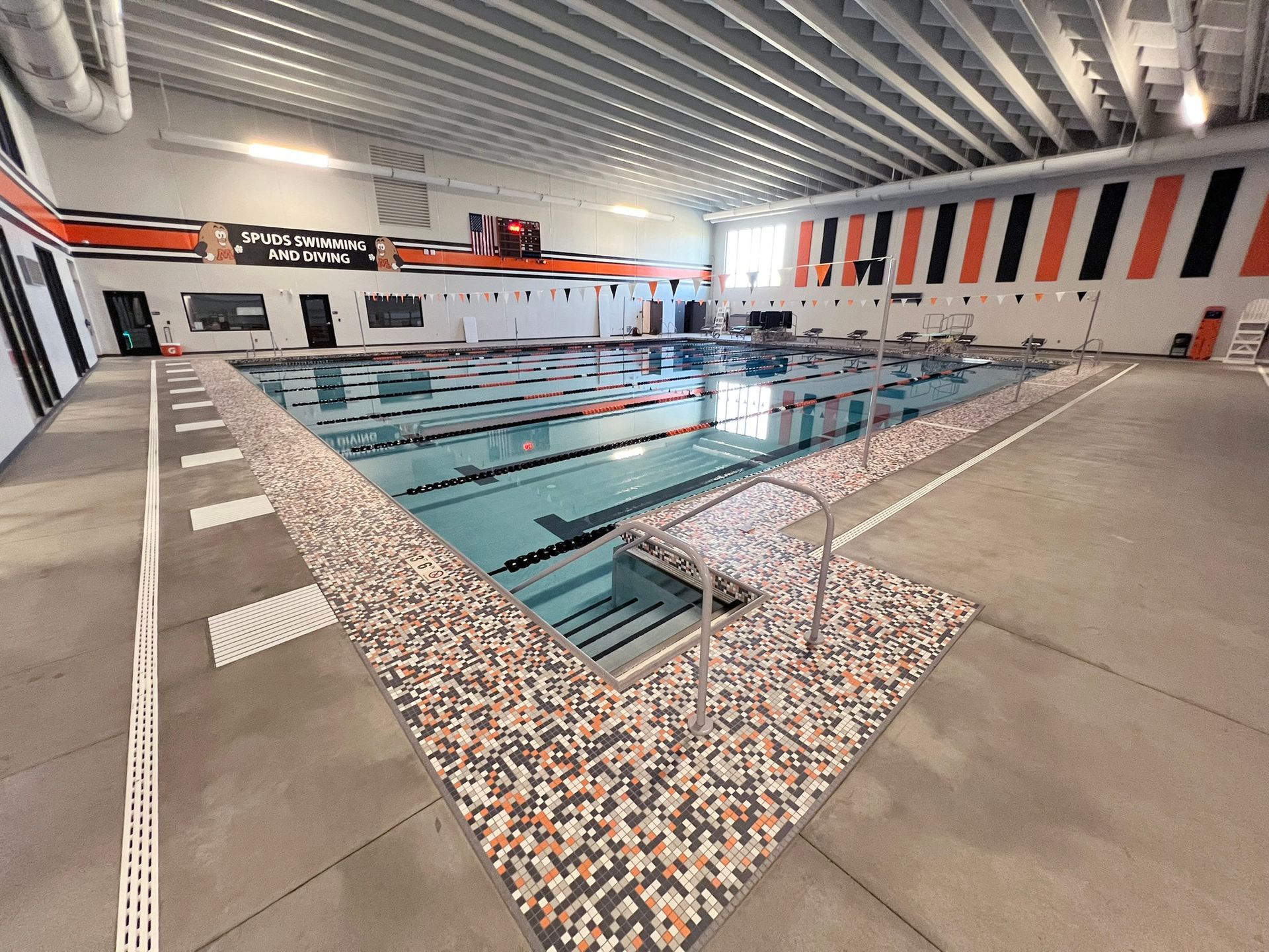 Indoor swimming pool with lane markers, orange and black accents.