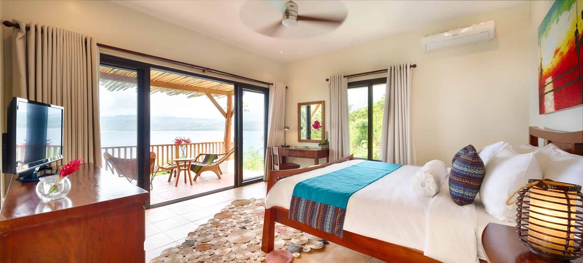 Bedroom with a wooden bed, balcony, and view of the sea.