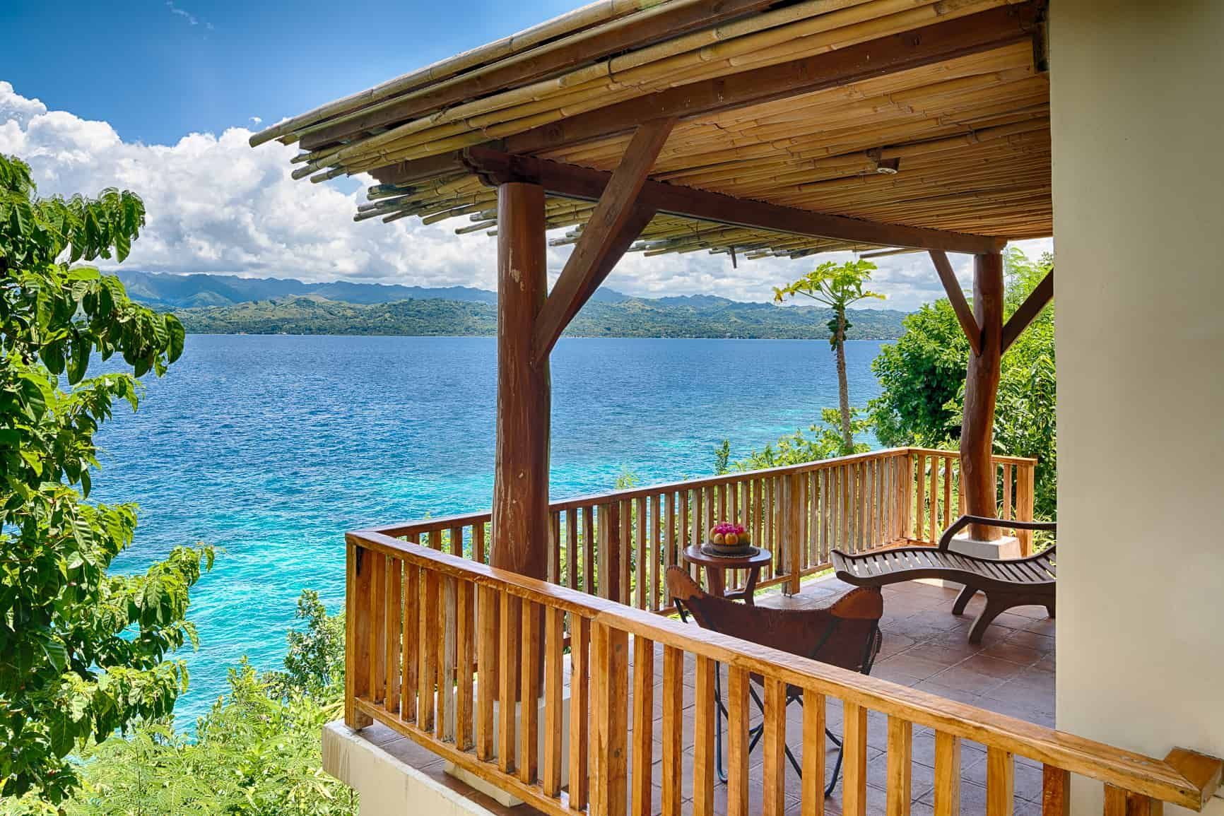 Wooden balcony overlooking blue ocean and distant islands.