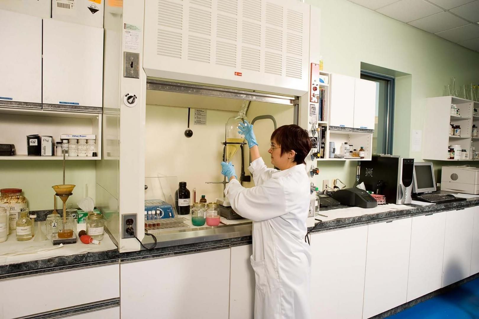 Une femme en blouse blanche travaille dans un laboratoire.