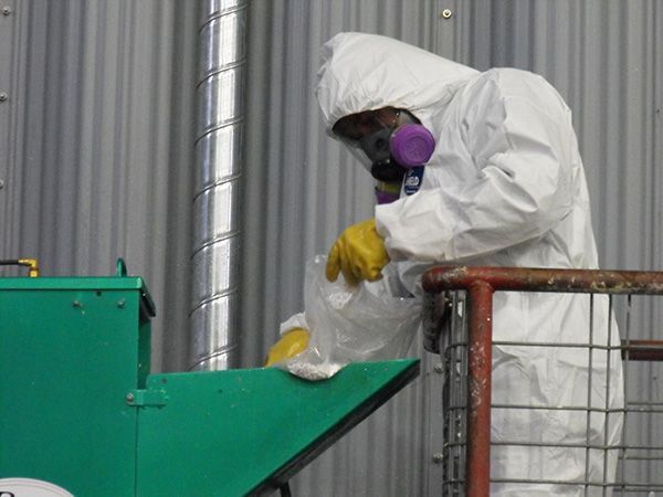 Un homme portant une combinaison de protection et un masque travaille sur une machine