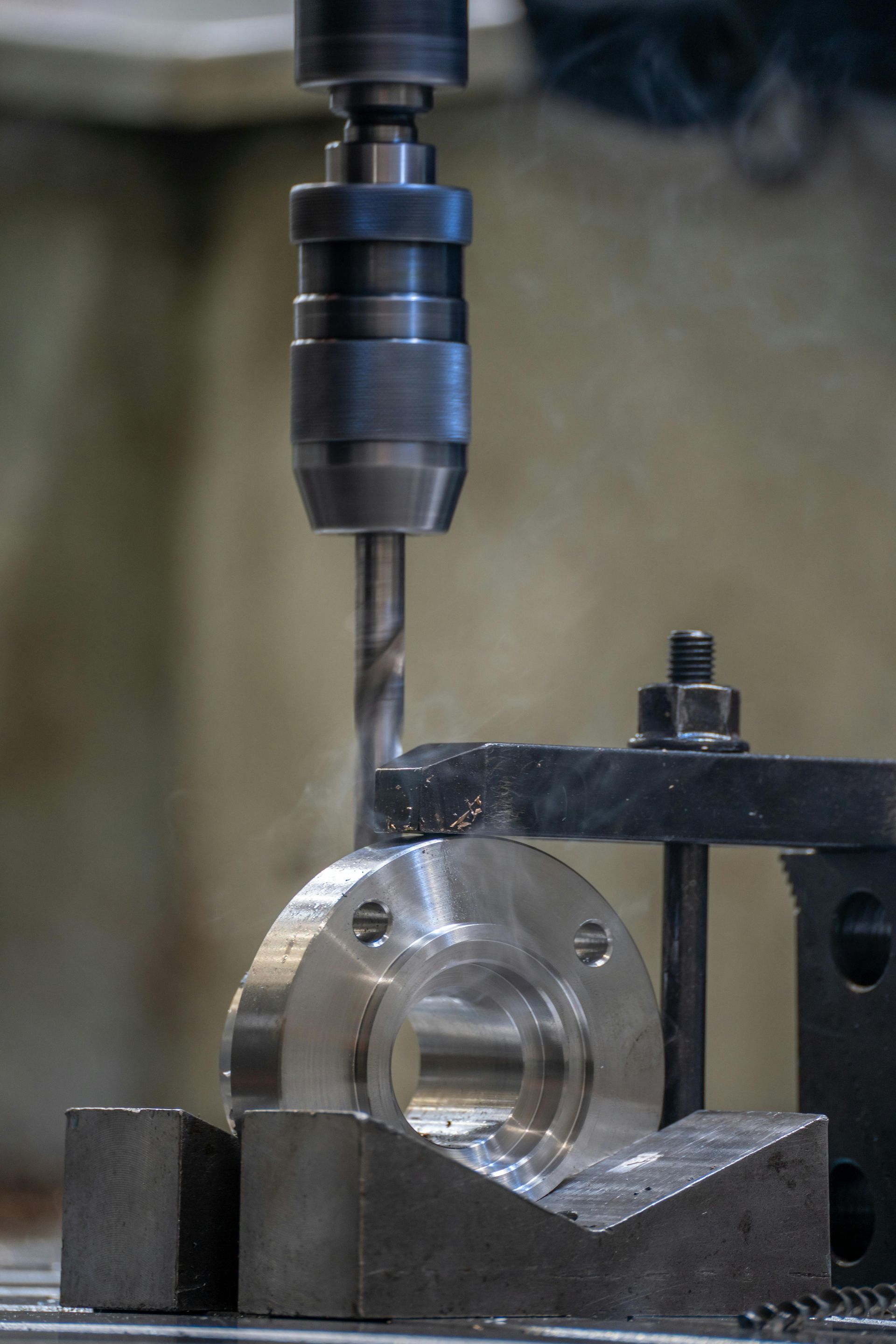 CNC milling machine drilling a metal part clamped in a vise