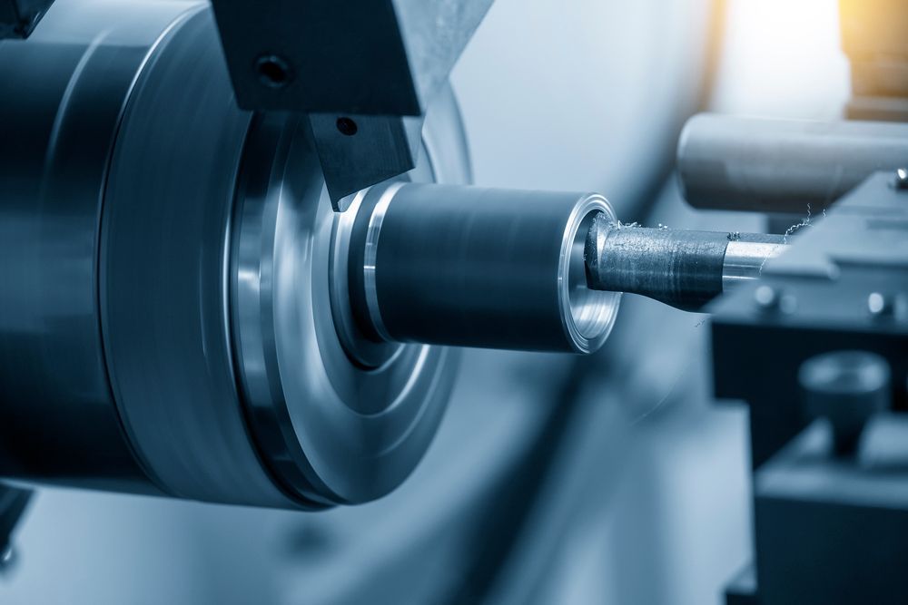 Metal lathe machining a cylindrical part in a workshop, with a spinning chuck and cutting tool close by