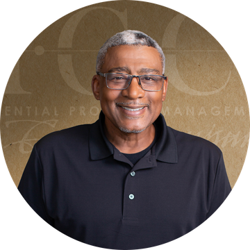 Smiling man wearing glasses and a black polo shirt, against a gold background.